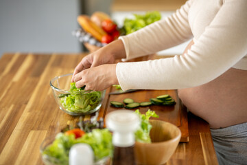 Pregnant Asian woman cooking healthy food at home