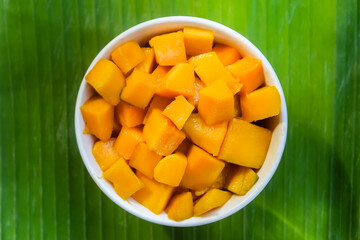 a bowl of cut mangoes on a banana leaf background.tropical fruit.