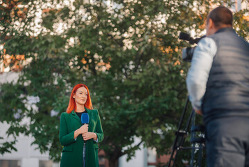 Journalist reporting live news outdoors with cameraman filming