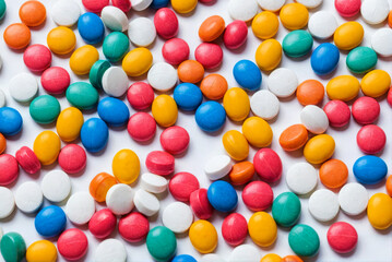 Obraz premium Multicolored tablets, capsules, pills densely scattered on white background. Assortment of pharmaceutical drugs, vitamins. Vibrant composition symbolizing healthcare, medication, and wellness.
