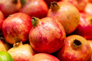 On a table lies a vibrant pile of pomegranates and limes