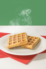 Freshly baked waffles on a white table and green background, Italian motif. Vertical - space for text