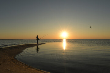 Side view teenage girl fishing at sunset Pamlico Sound