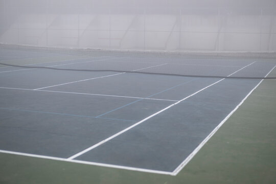 blue tennis court enveloped in grey blurring fog