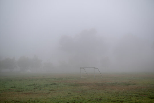 Single soccer goal in park covered in thick dense grey fog