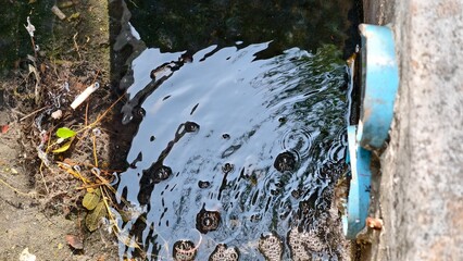 Calm Surface with Bubbling Water and Debris Near Drainage Pipe on Urban Environment