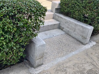 Stone Steps Surrounded by Green Shrubs Leading to an Outdoor Pathway in a Public Space Setting
