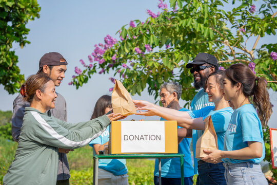 diverse group of charity volunteers giving donation things to poor and disadvantaged people,helping the needy to distribute of food items and water in rural