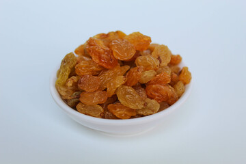 Raisins in a small white bowl, isolated on white background