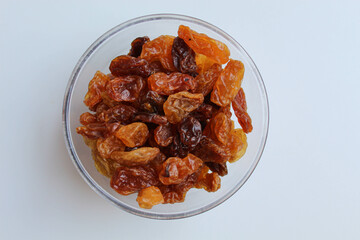 Raisin in a transparent bowl, isolated on white background, flat lay or top view