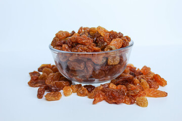 Overflow raisins from a transparent bowl, scattered, isolated white background