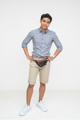 Southeast Asian man standing with hands on hips, wearing a casual outfit and waist bag, exuding...