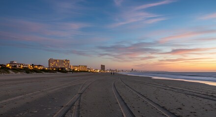 Panoramic Sandy Beach Receding Towards Illuminated Hotels Under Wide Sky With Wispy Clouds Transitioning From Deep Blue To Warm Hues During Twilight
