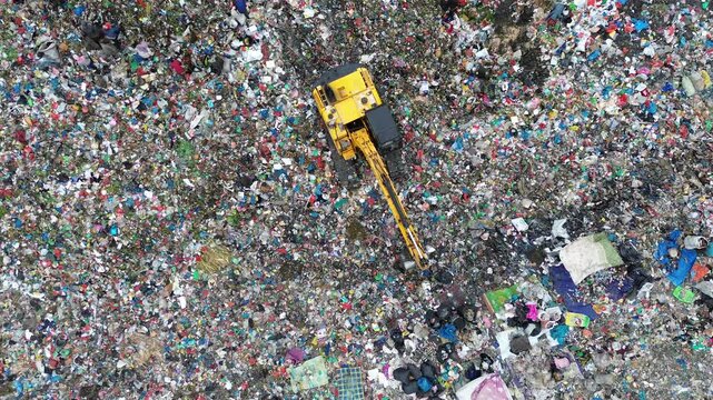 Heavy machinery operating on top of massive garbage landfill site
