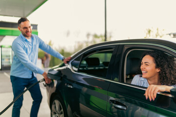 Friendly gas station attendant fueling a customer's car while the happy woman driver relaxes inside, enjoying the seamless service and convenience of the modern filling station
