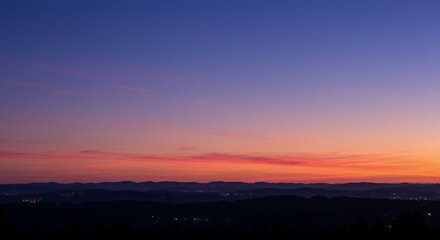 Fototapeta premium Vibrant Twilight Skyscape with Indigo Lavender Peach Gradient Over Silhouette of Rolling Hills in Serene Early Summer Dawn