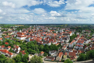 Eine beeindruckende Luftaufnahme von Günzburg, einer charmanten Stadt in Bayern. Die Stadt ist geprägt von einer harmonischen Mischung aus historischen und modernen Gebäuden mit roten Ziegeldächern.