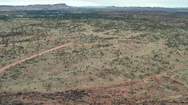 Aerial view looking west along Udoolya Road with Alice Srings, Mparntwe in the distance. Northern Territory, Australia. August 2022.