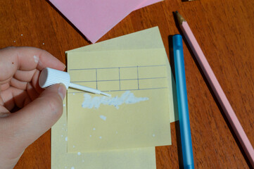 Hand applying correction fluid to paper table on sticky note. Office supplies, error correction,...