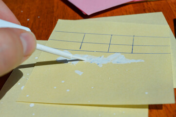 Hand applying correction fluid to paper table on sticky note. Office supplies, error correction,...