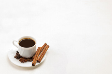Cup of coffee, cinnamon sticks and star anise on saucer