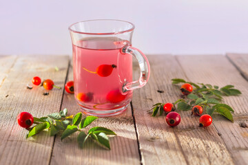 rose hips tea in glass cup on wooden background