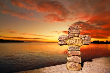 Stone cross with the names of Jesus Christ written on them. Background has a wonderful red sunset...