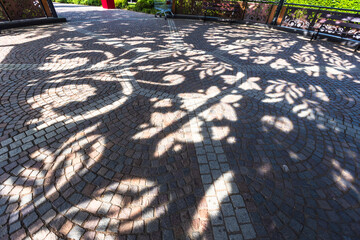 Abstract view of textured cobblestone or stone brick pavement with strong, intricate shadows cast...