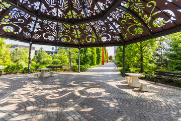 Ornate Metal Gazebo with Floral Cutouts Overlooking Manicured Park and Stone Patio Seating