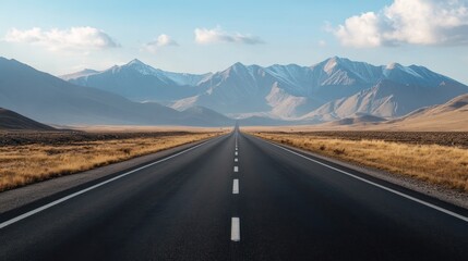 Endless highway leading to snow-capped mountains under a serene sky