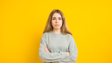 Fototapeta premium Serious young woman crossing arms on yellow background