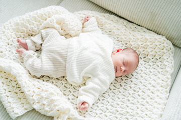 Closeup of cute newborn baby boy in light clothes at home. Eco Baby bed. Home.