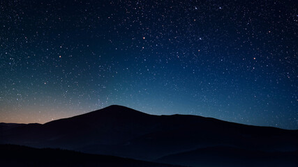 a a movement of stars in the night sky with the view of mountains.