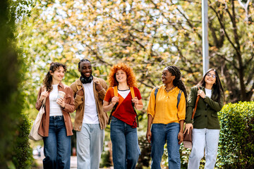 Students enjoying a sunny day on campus while walking together and sharing smiles around a green area