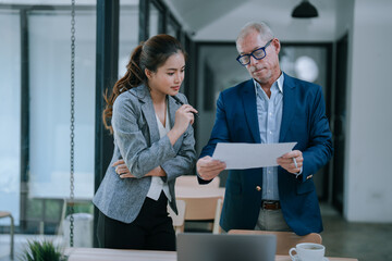 Senior businessman presenting a document to young businesswoman while collaborating on a new...