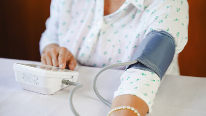Woman measuring blood pressure at home, close up of arm with cuff, health monitoring, calm atmosphere