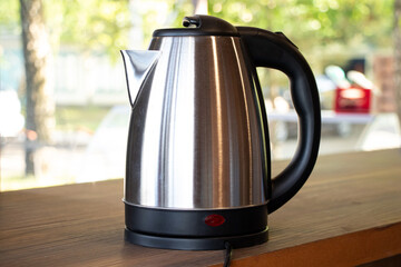 Electric steel kettle stands on the table outside