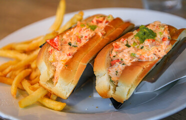 Tasty fresh lobster roll sandwiches with potato french fries on a white plate at a restaurant in Newport Beach, California, New England lobster