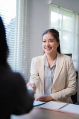 Two businesswomen shaking hands after finalizing a contract, expressing joy over the successful...