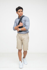 Southeast Asian man looks alert and holds his sling bag tightly, appearing cautious and protective of his belongings. Isolated on a light background.