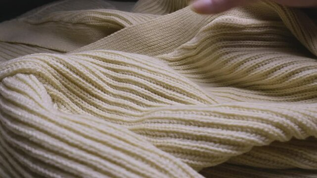 Hand feeling the texture and ribbed pattern of a knitted Wool jumper