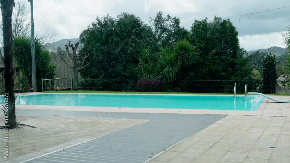 Poster large empty pool with cloudy skies and wet tiles in calm outdoor setting