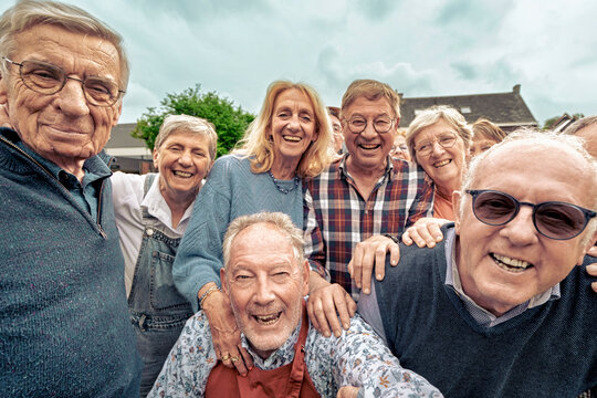 Happy senior friends group selfie outdoors, laughing together in retirement