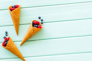 Summer breakfast with fresh berries in waffle cones on mint gree