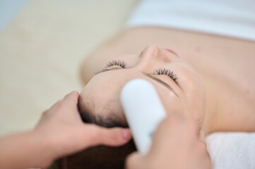 Naklejka premium Female Facial Massage Therapy with Beauty Device at Spa