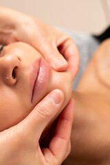Close-up of a facial massage session, with hands gently massaging a woman s chin and jawline.