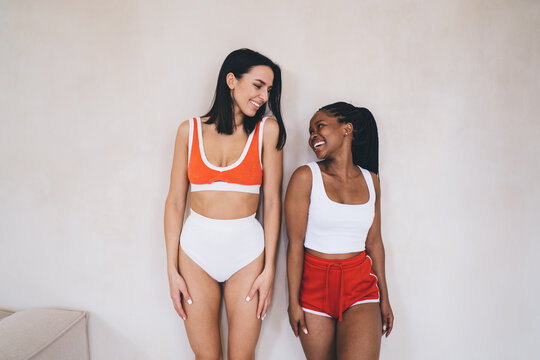 Genuine connection between smiling diverse workout buddies 20s. Cheerful Fitness friends in stylish athletic wear showcase natural happiness and body positivity during together time spending