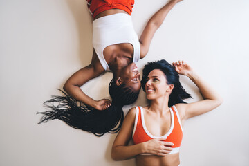 Serene moment between athletic companions smiling while lying down. Happy diverse Women sharing...