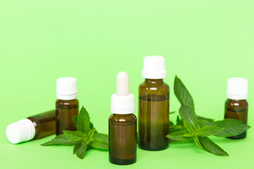 Natural Mint Essential Oil in a Glass Bottle. organic cosmetics with herbal extracts of mint on colored background
