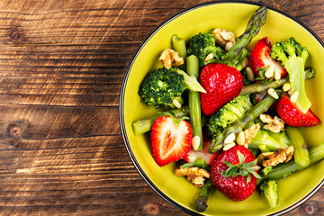 Green mixed salad with green asparagus and strawberries.